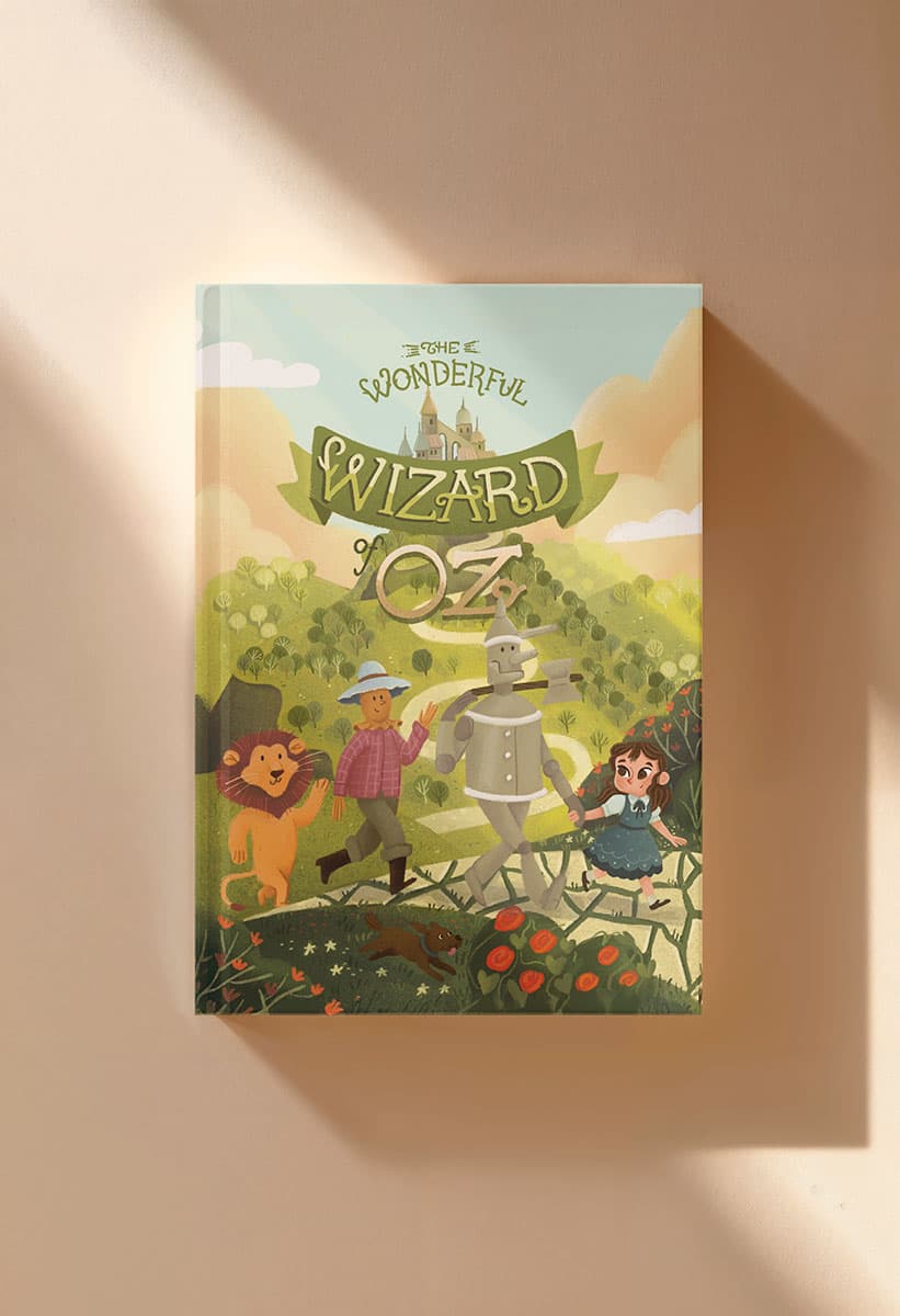 Mock-up photo of the Wizard of Oz illustration used as the cover art for a printed book, placed on a light tan surface with a shadow.